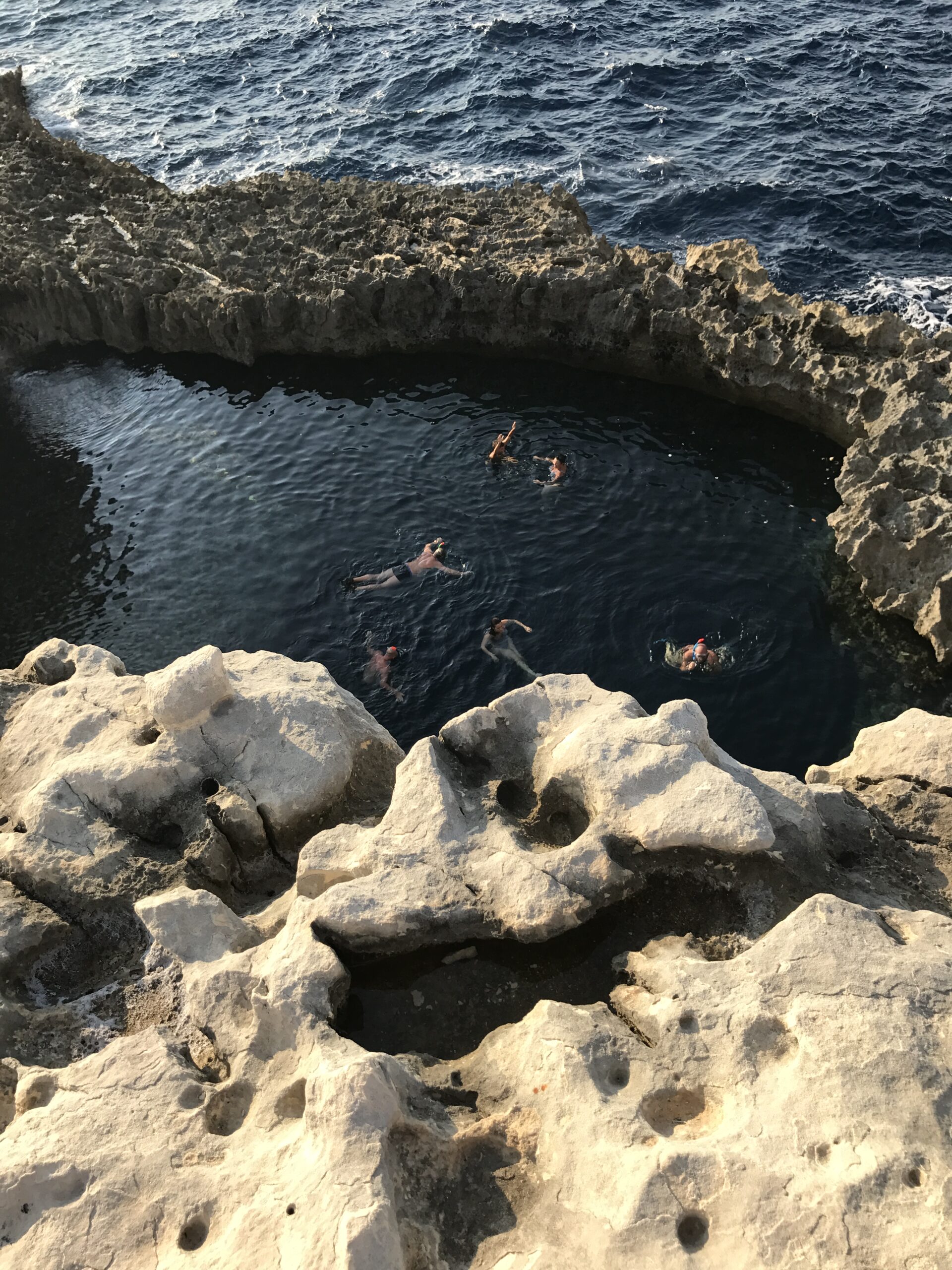 people swimming in rock hole